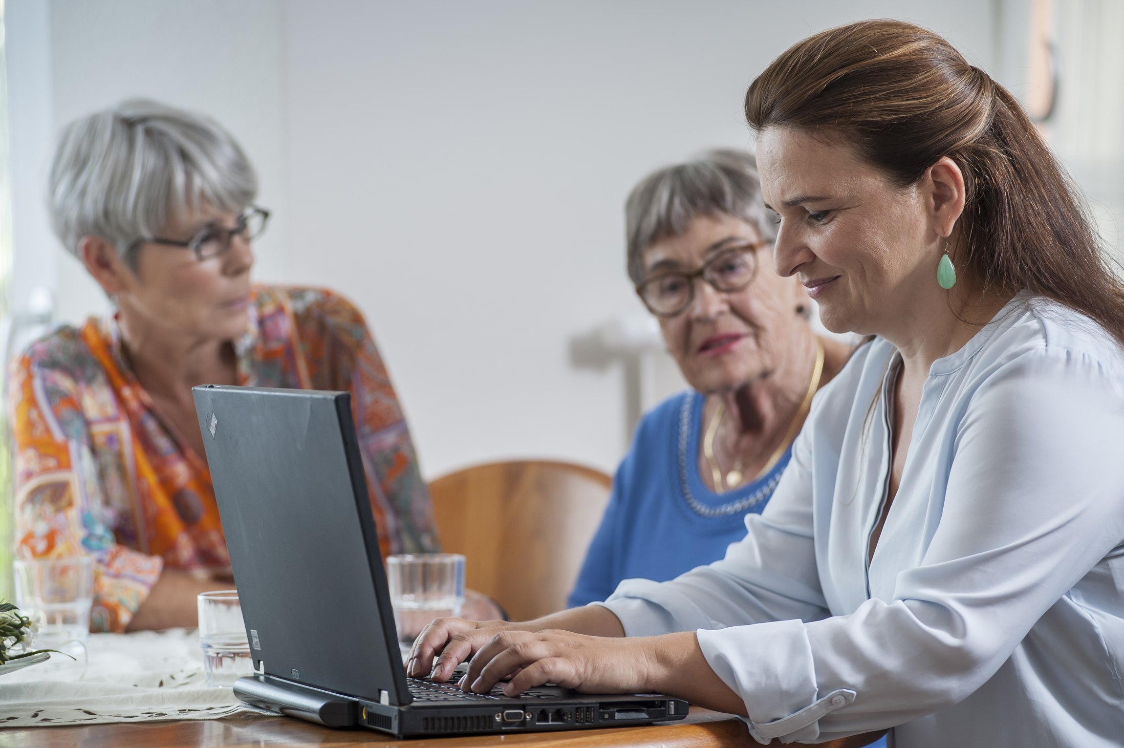 Ärztin am Laptop mit zwei Seniorinnen neben sich
